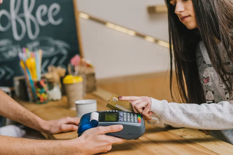 midsection young woman paying with mobile phone waitress cafe